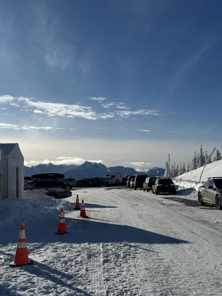 Parked cars and cones in the snow below the Ridge peaks